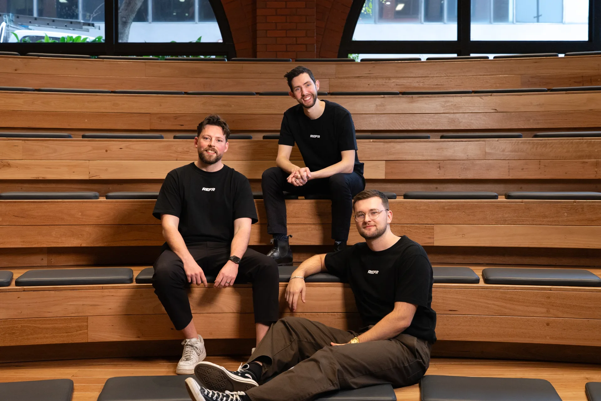 The Refr team sitting on the tiered timber seating at their Melbourne office